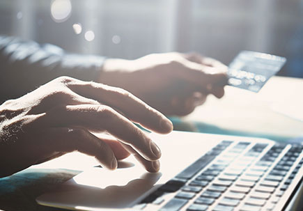 Hand holding credit card paying for something online via a laptop Hand holding credit card paying for something online via a laptop