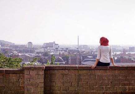 Woman sat on a wall with her back to you looking out over the city Woman sat on a wall with her back to you looking out over the city