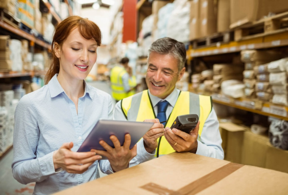 man and woman working in a warehouse looking over a tablet