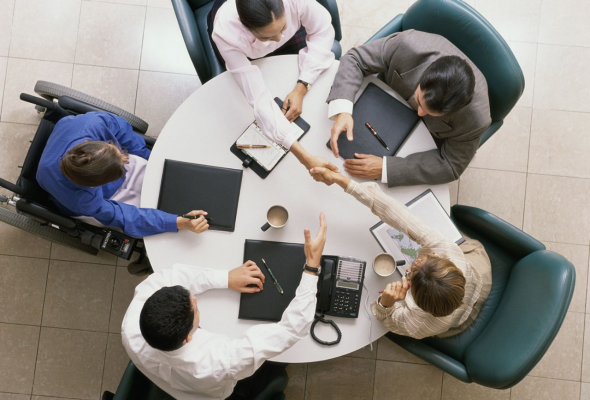 People having a meeting around a round table.