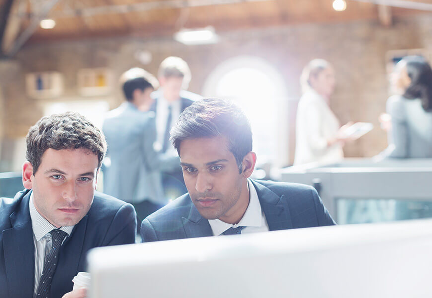 Two men in an office look intently at a screen