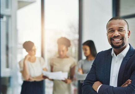Man smiling with crossed arms, with people behind him Man smiling with crossed arms, with people behind him