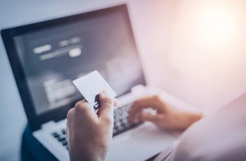 Hand holding credit card paying for something online via a laptop Hand holding credit card paying for something online via a laptop