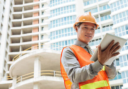 Workman using a tablet outisde a building