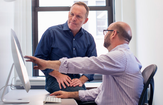 A worker showing another colleague what’s on his screen A worker showing another colleague what’s on his screen